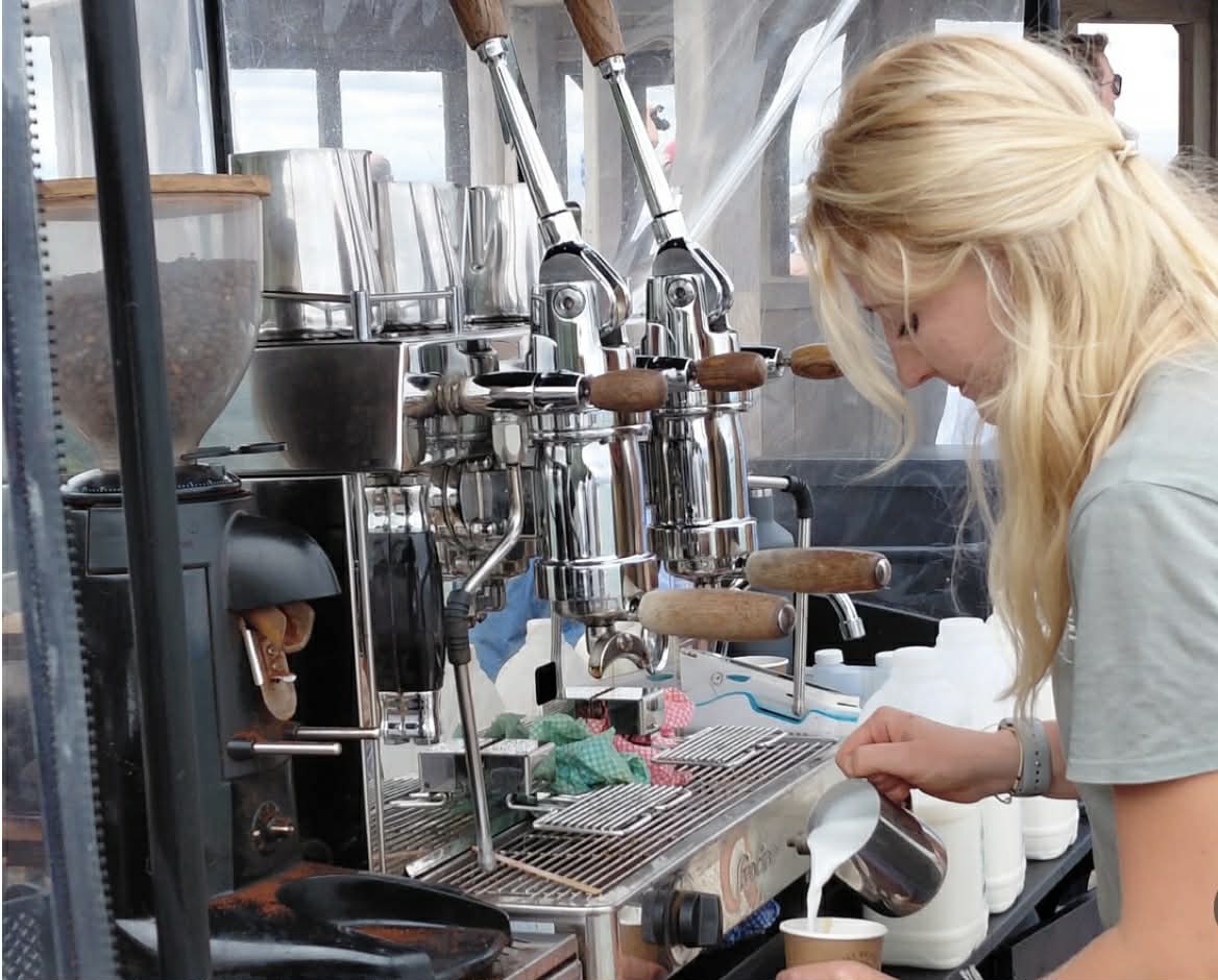 Lady pouring milk into a coffee cup